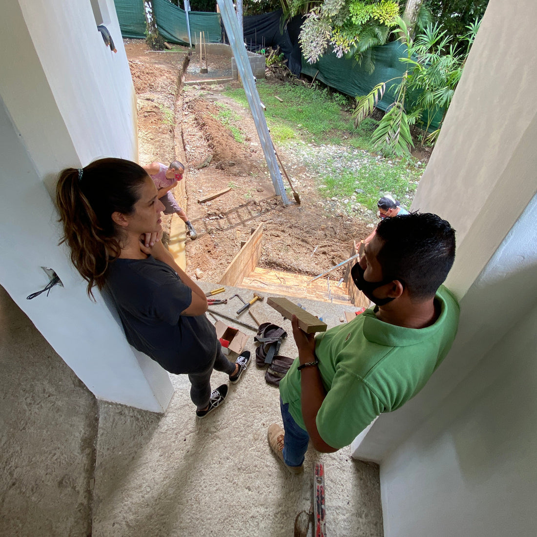 Two people working on a construction site with tools and equipment.